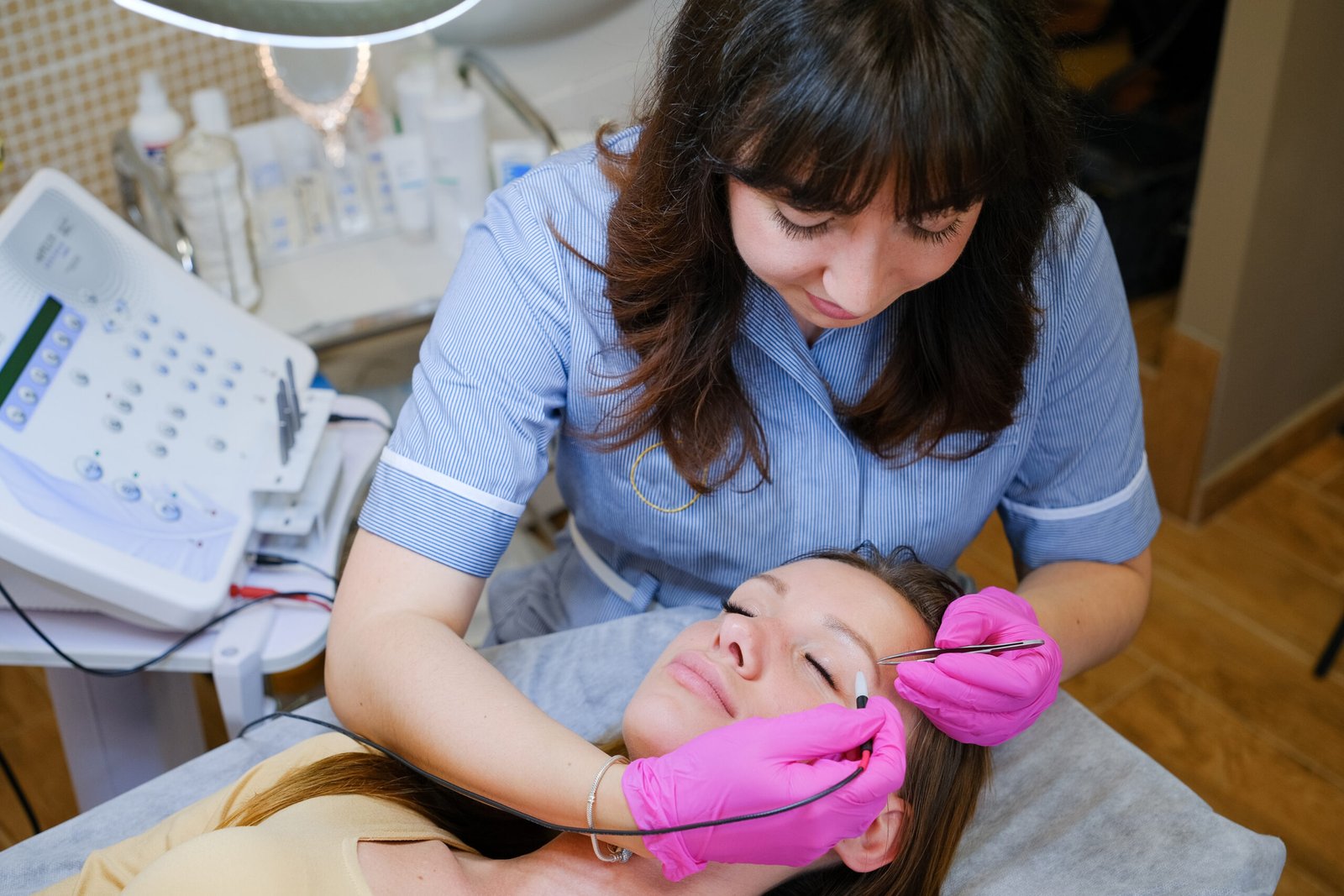 Young beautiful female dermatologist doing hair removal treatment on patient's face with electrolysis. Epilation and beauty concept. High quality photo